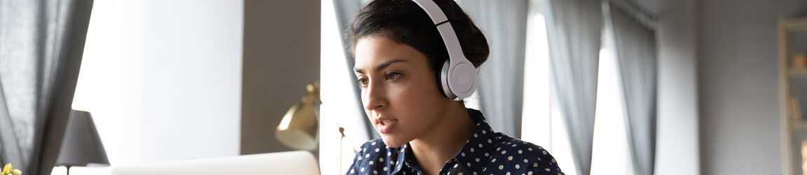 woman with headphones, looking at a computer