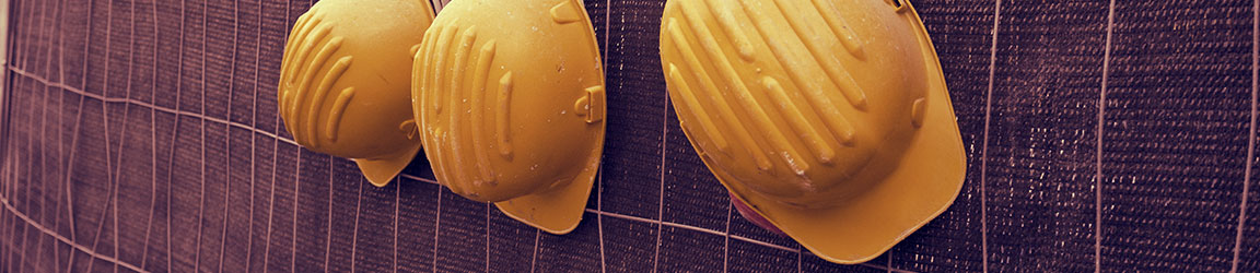 Three hard hats hanging on a fence