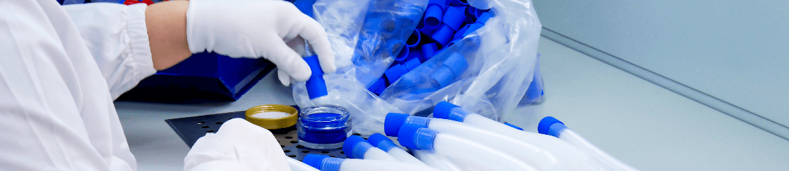 Une travailleuse de dispositifs médicaux portant des gants protectifs et une blouse de laboratoire construit un appareil de respiration artificielle à son poste.